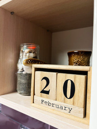 A closeup of a wooden desk calendar displaying February 20, accompanied by decorative items.の写真素材