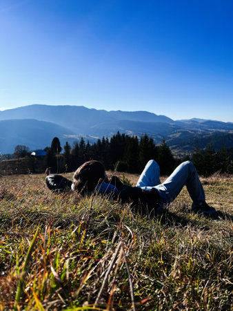 A serene outdoor moment featuring a person lying in a grassy meadow, surrounded by scenic Carpathian...