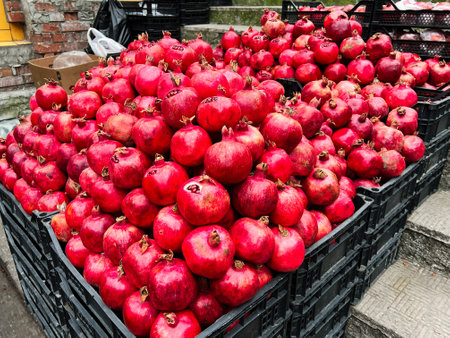 A vibrant display of red pomegranates arranged neatly in plastic baskets at the marketの写真素材