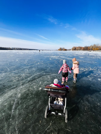 Children and a baby stroller on a frozen lake during a sunny winter day