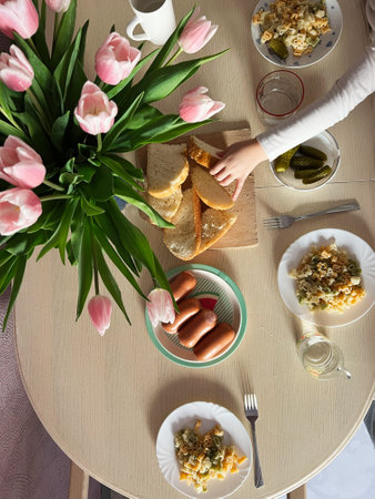Breakfast table with a variety of food and pink tulips for family enjoymentの写真素材
