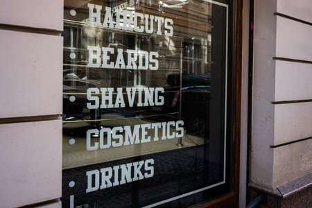Glass window of a barber shop displaying haircut and beard services.の写真素材
