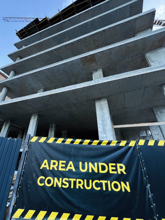 A multi story building under construction with a warning sign for safety and caution.の写真素材