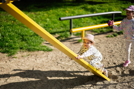 Smiling children enjoying a sunny day on a seesaw in the playgroundの写真素材