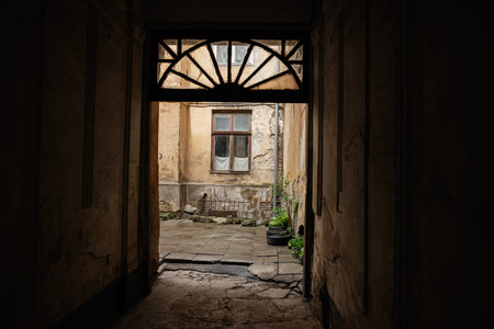 Weathered courtyard seen through a shadowed passage, highlighting aged walls and textures.の写真素材