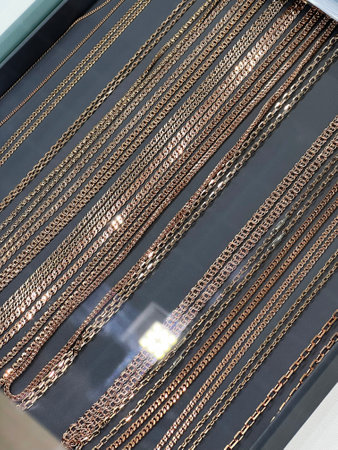 Elegant display of gold and rose gold chains on a dark background.