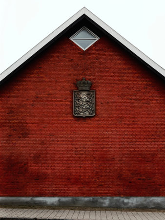 A red brick facade features a crest symbol and symmetrical roof design. Copenhagen, Denmark.の写真素材