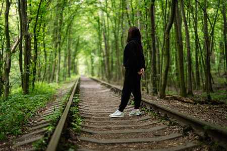 A serene scene featuring woman on railway tracks amidst a verdant forest