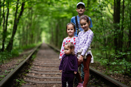 Four children posing on an old railway surrounded by lush green forestの写真素材