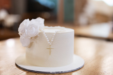 White cake topped with a religious rosary necklace and flower detailの写真素材