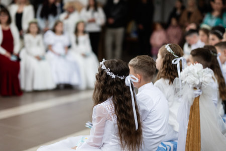 Young children participating in a first communion event with ceremonial attire and decor