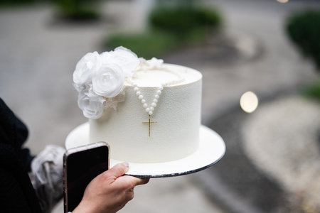White cake adorned with a rosary and flowers, perfect for religious ceremonies