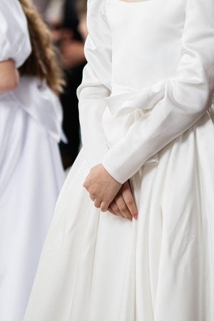 Young girl in white communion dress at a ceremonial gatheringの写真素材