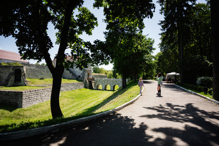 People strolling near historic stone ruins in a green parklit area with trees.の写真素材