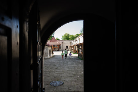 A family walks through a historic stone courtyard surrounded by traditional wooden buildings.