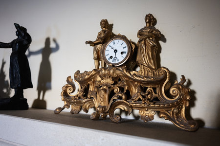 Antique golden clock adorned with sculptures, showcasing intricate craftsmanship and historical...