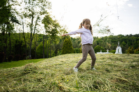 Child having fun outdoors in a grassy area surrounded by nature on a sunny dayの写真素材