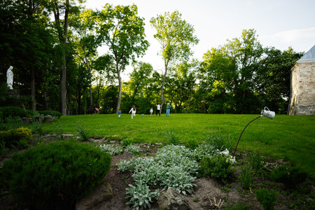 A peaceful garden with people playing outdoors surrounded by vibrant trees and plants