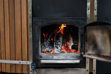 Close view of a burning outdoor stove showcasing warmth, firewood, and rustic charm.の写真素材