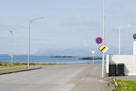 Seaside urban street in Akranes, Iceland, featuring blue water and mountain views.の写真素材