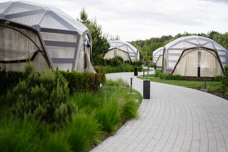 Dome tent accommodations for glamping surrounded by lush green environments and pathways