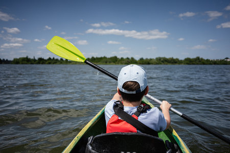 A child kayaking on a peaceful lake during a bright sunny day
