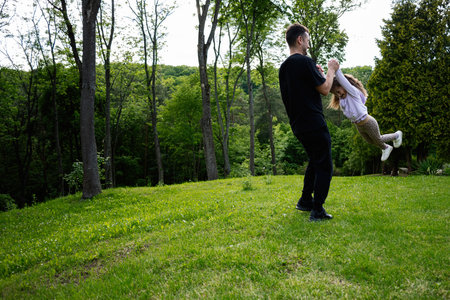 A joyful father and daughter playing together on a sunny day in nature