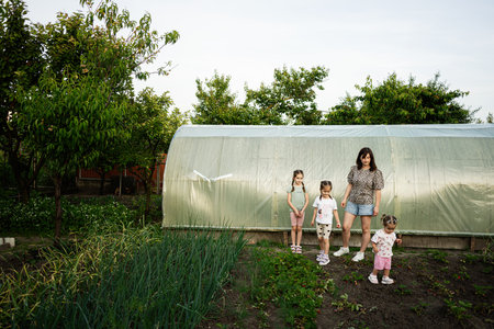 Family enjoying time together outdoors by a greenhouse in a lush gardenの写真素材