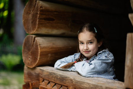 A young girl posing cheerfully near a wooden structure in a natural environmentの写真素材