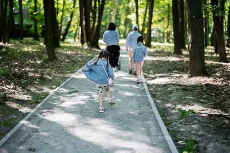 Family spending time together walking through forest pathway in serene park setting.の写真素材