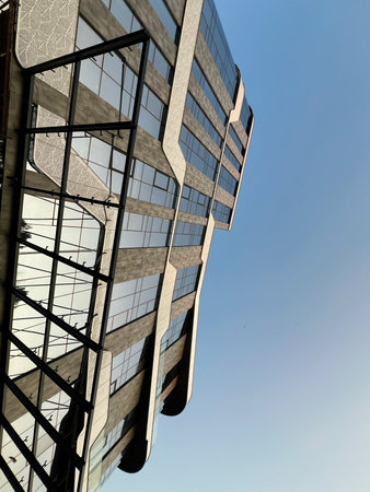 Angled view of geometric glass building reflecting the sky, showcasing contemporary design