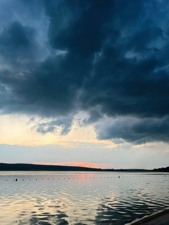 Serene overcast sunset scene featuring a peaceful lake and tranquil waters reflecting lightの写真素材