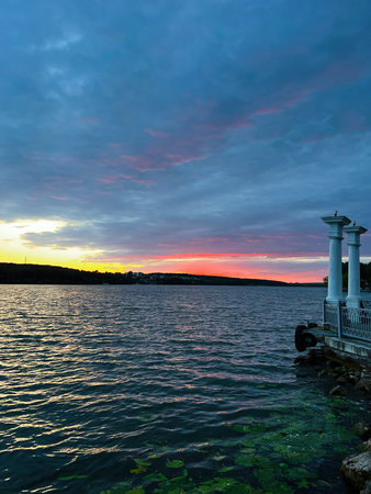 Vibrant sunset over a calm lake with vivid colors and serene surroundings.の写真素材