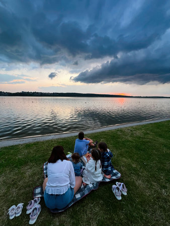 A serene family gathering enjoying an evening picnic with a beautiful sunset view.の写真素材