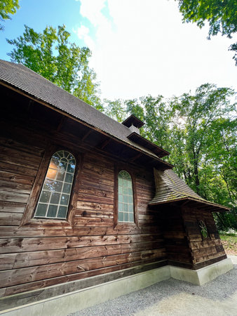 A traditional ukrainian wooden church facade surrounded by lush green forest under a blue skyの写真素材