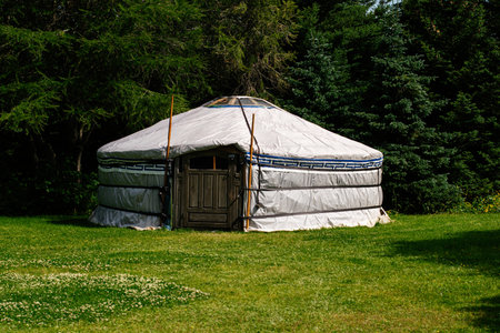 Circular yurt set on green grass surrounded by trees in Reykjavik, Iceland.