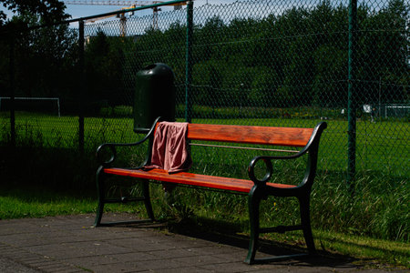 Wooden bench in Reykjavik park, scenic green surroundings, chain link fence behindの写真素材