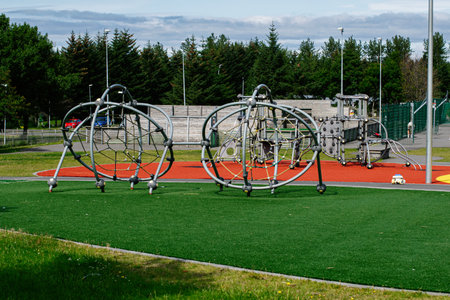 Modern playground structures in Reykjavik park featuring unique climbing equipment and greenery