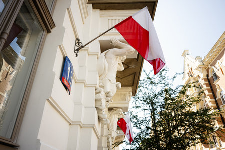 Red and white national flag suspended on a classical structure downtownの写真素材