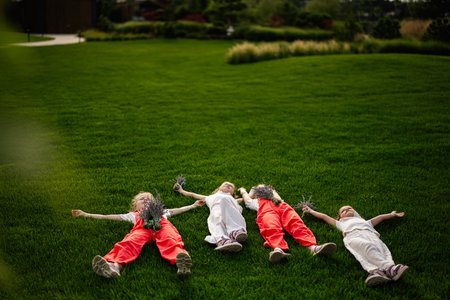 Four kids enjoying leisure time while holding flowers in a vibrant grassy parkの写真素材