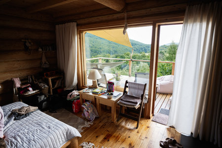 Rustic cabin interior showcasing a serene outdoor view and natural wooden furnishings.の写真素材