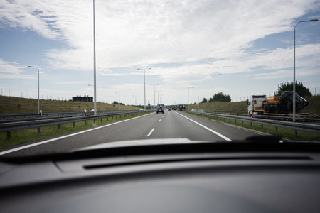 Vehicles traveling on a highway under a partly cloudy sky in Poland