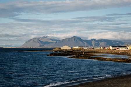 Beautiful coastline with distant mountains, ocean, and peaceful village scenery in Iceland.