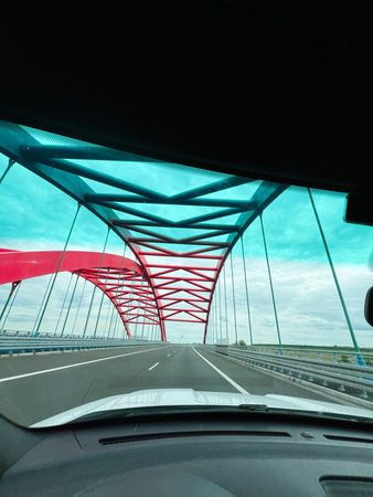 A view from a car driving over a colorful arch bridge with blue skiesの写真素材