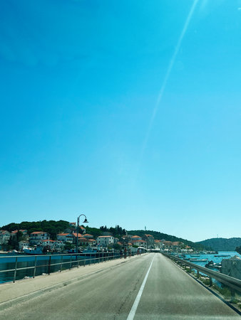 A serene coastal view showcasing Rogoznica bridge with picturesque buildings and clear sky in...