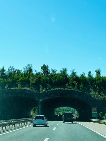Zagreb, Croatia - August 25, 2025: Vehicles moving on a highway under an eco-friendly bridge in clear weather in Croatia.の写真素材