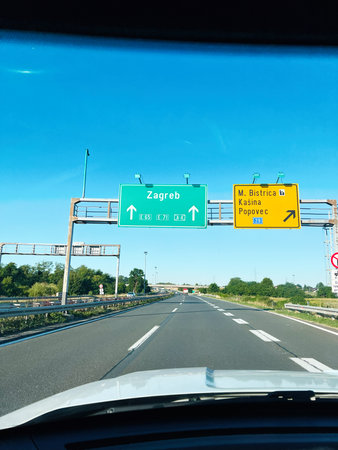 Driving on a bright sunny day with highway road signs leading to destinations.の写真素材