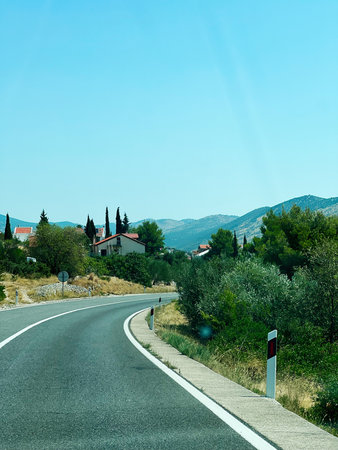 Curved road with greenery and houses, surrounded by scenic nature and clear sky in Grebastica, Croatia.の写真素材