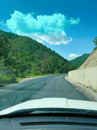 Freshly paved road winding through mountains surrounded by lush green landscapes