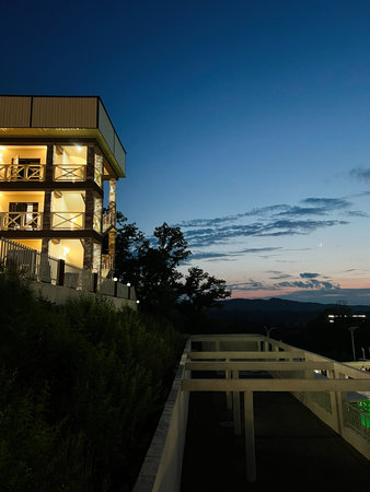 A contemporary building lit up against a scenic twilight backdrop of nature.の写真素材
